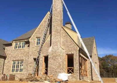 New home chimney construction very tall with ladders on each side and new chimney cover