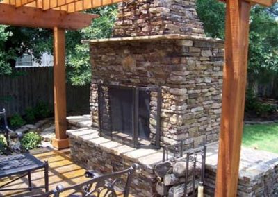 Beautiful stacked stone stone outdoor fireplace with cedar posts on each side and table and chairs
