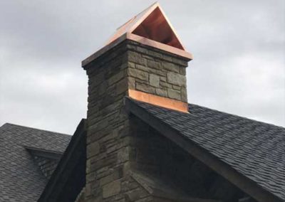 Stone chimney with copper flue cover