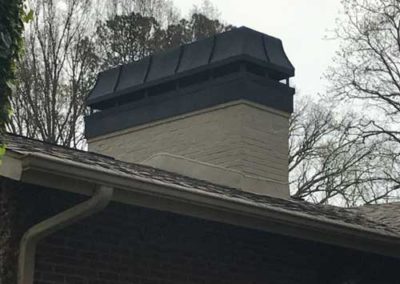 Large white chimney with black cap and flue cover