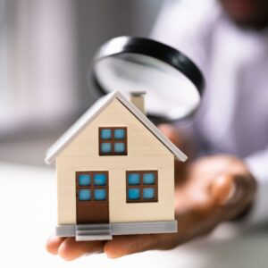 a person looking through a magnifying glass at a small fake house